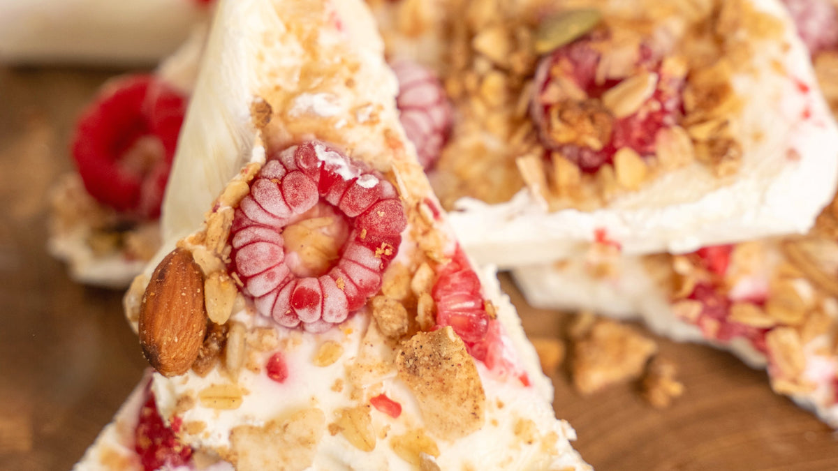 Close-up of frozen coconut yoghurt bark topped with raspberries and low sugar granola.