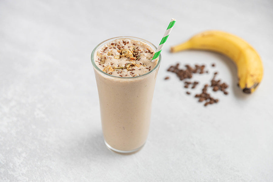 Coffee protein shake topped with prebiotic granola and a green striped straw