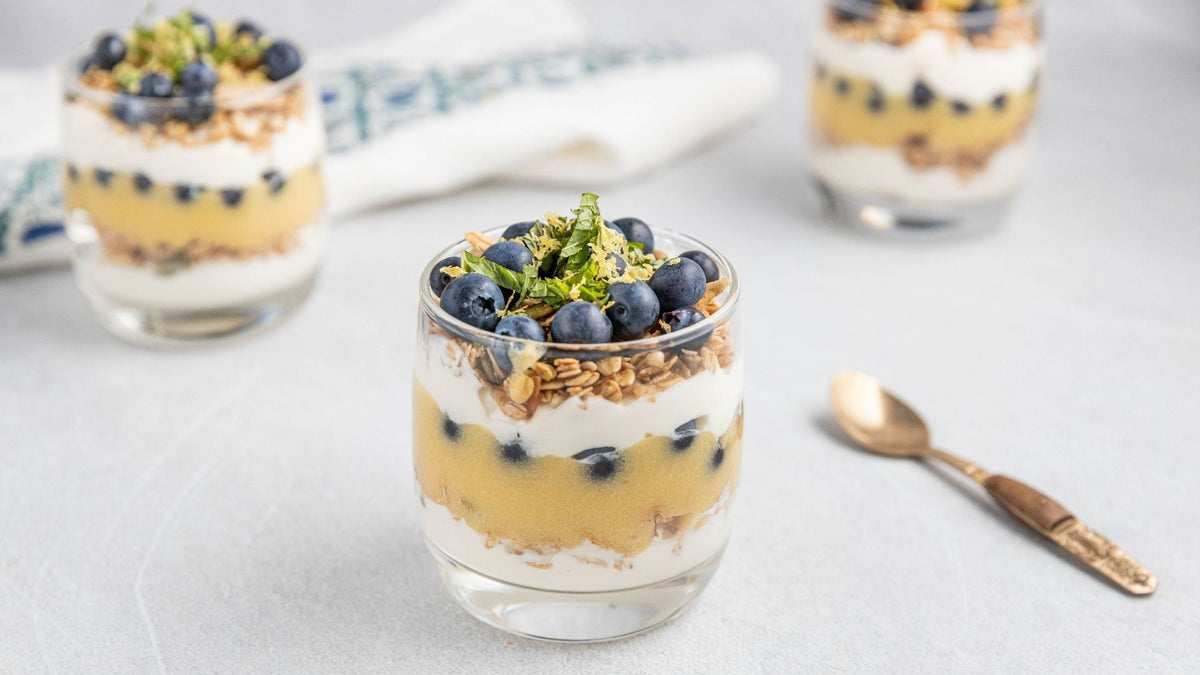 Toasted muesli parfaits with olive oil lemon curd and fresh blueberries in glass jars.